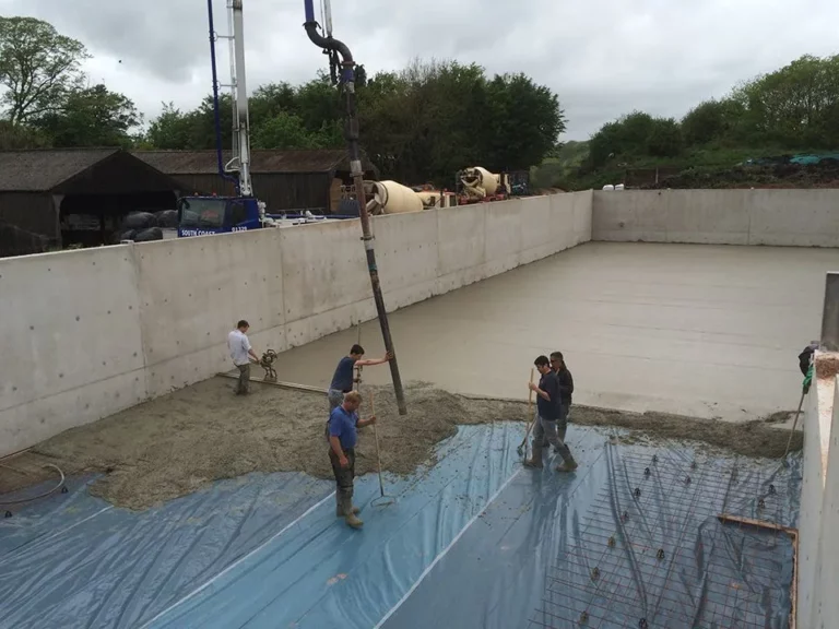 Concrete pour in progress using crane hose on prepared ground.