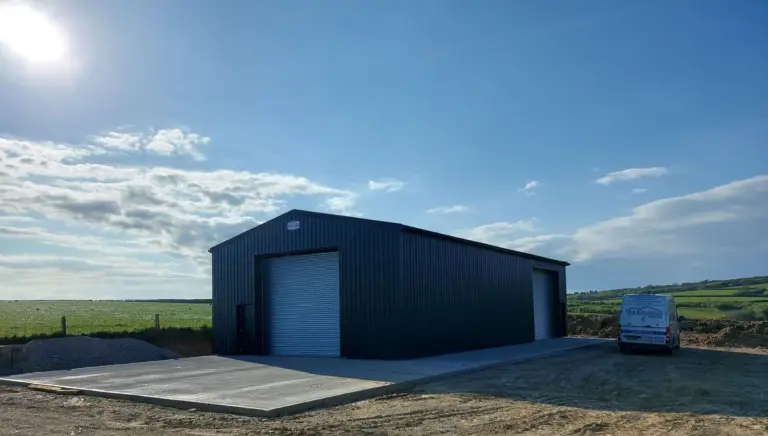 a large metal structure with exterior concrete flooring erected in a field on a bright, sunny day