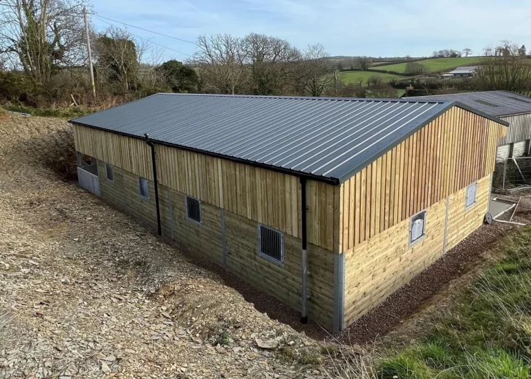 Wooden cladded outbuilding in rural setting with grey roof.