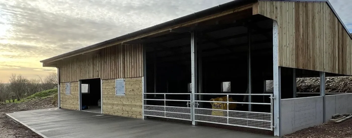 Open-fronted steel building with metal fencing and cattle gates.